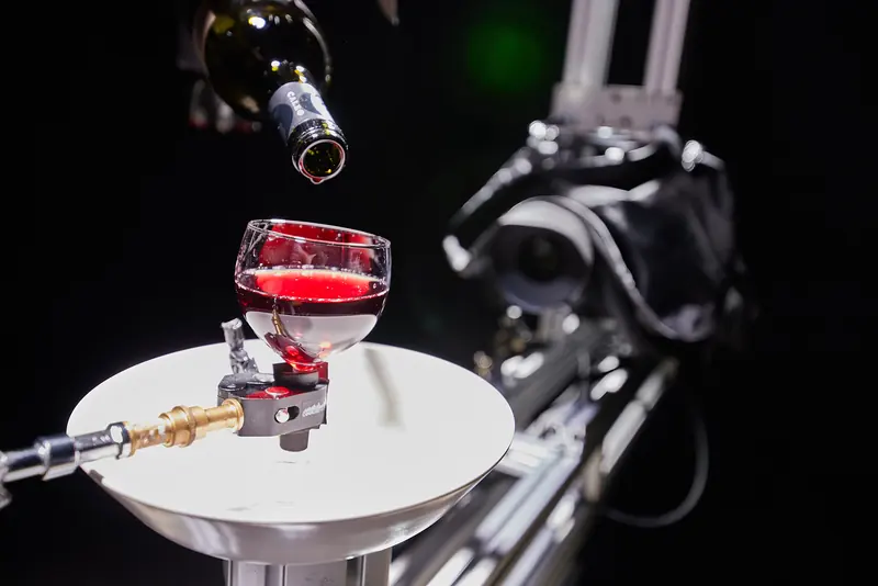 Tabletop-Dreh: Rotwein wird in ein beleuchtetes Glas gegossen, daneben die Kamera