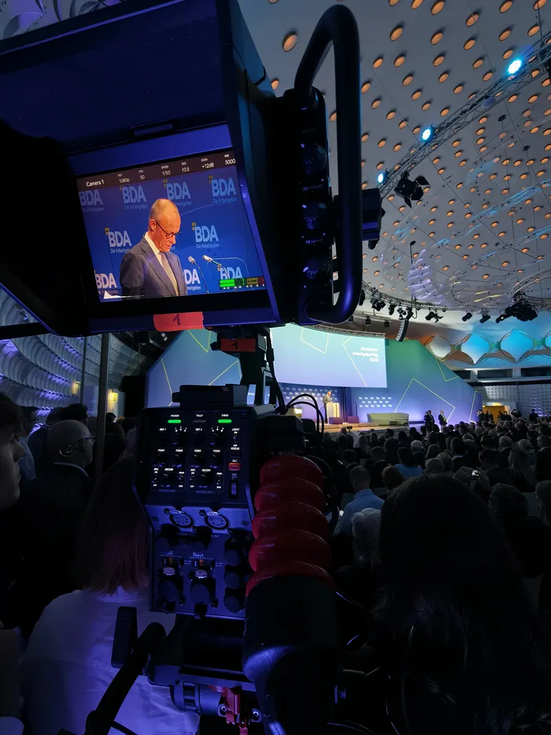 Studiokamera mit Sucher in einer großen Kongresshalle – im Bild die Rede von Bundeskanzler Friedrich Merz