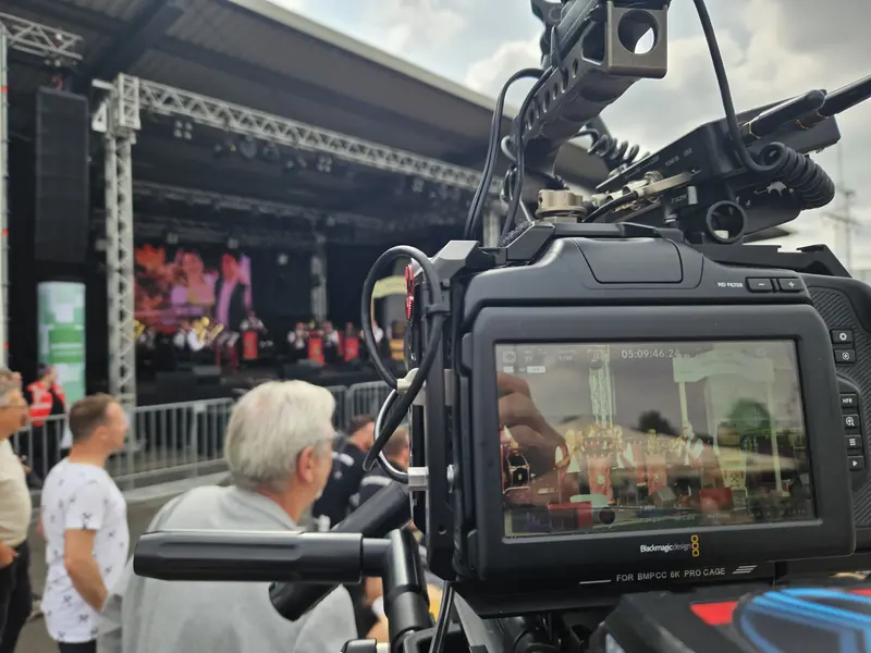 Kamera mit Monitor vor einer Open-Air-Bühne, auf dem Display das Livebild